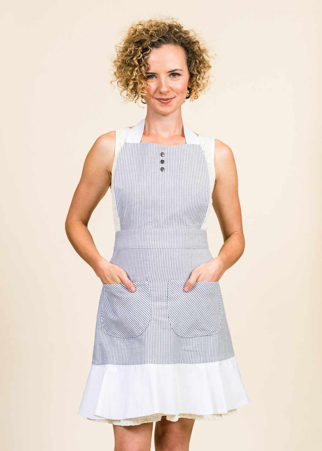 Proudly wearing her black and white seersucker apron with white ruffle, an attractive woman faces the camera