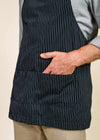 Closeup of black apron with pockets, with a hand in one pocket.