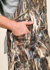 A closeup of a hand in the pocket of a camo apron