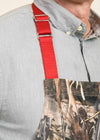 Closeup of the shoulder strap of a camoflauge apron with red strap, on a man wearing a gray-blue shirt