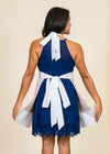 Brunette woman with back to the camera wearing a blue dress and an apron with thick white straps