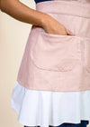 closeup of a wrist with a hand sticking in the hip pocket of a red and white apron