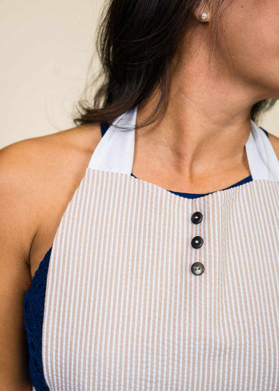closeup of the front of neck of a brown-haired woman wearing an apron with black buttons on sternum