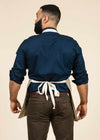 rearview of large man with beard wearing a blue shirt and a sawgrass fabric apron with white stripes