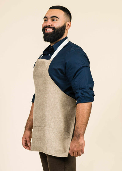 profile shot of large man with beard wearing a blue shirt and a sawgrass fabric apron with white stripes